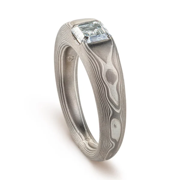 Cathedral style ring with a single diamond set into it, the stone is a soft square shape, the band is light gray and silver in color and tapers towards the underside of the ring.