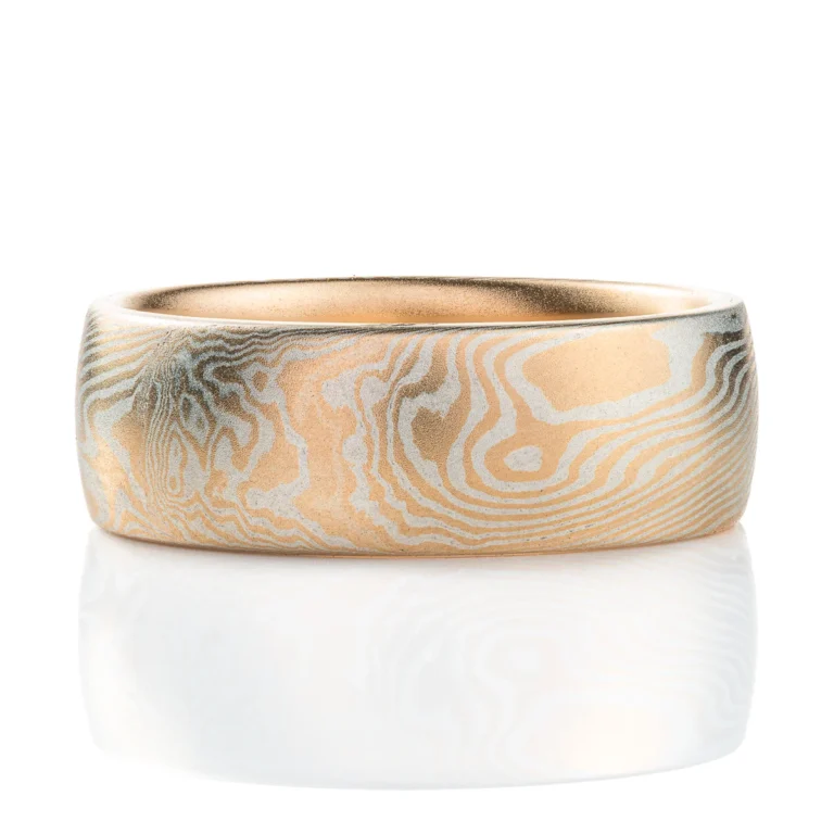 smooth surface domed wedding band, wide. smooth surface, layers of yellow gold and sterling silver twisting and running on a diagonal pattern around the ring