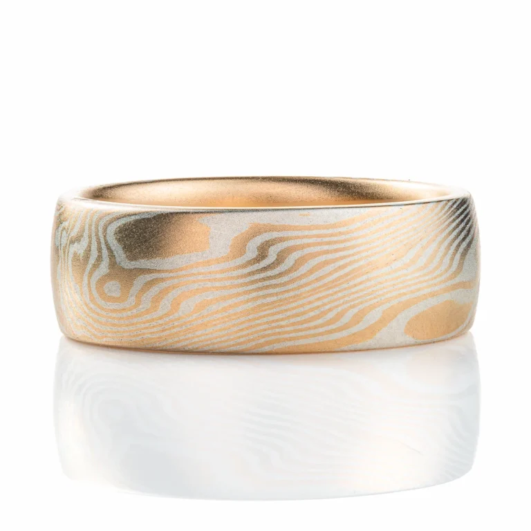 smooth surface domed wedding band, wide. smooth surface, layers of yellow gold and sterling silver twisting and running on a diagonal pattern around the ring