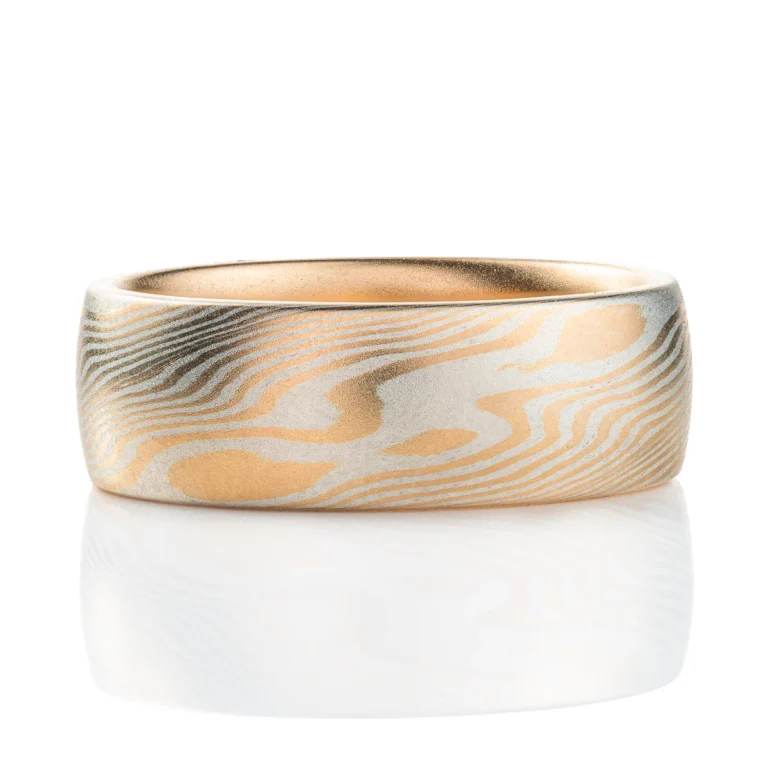 smooth surface domed wedding band, wide. smooth surface, layers of yellow gold and sterling silver twisting and running on a diagonal pattern around the ring