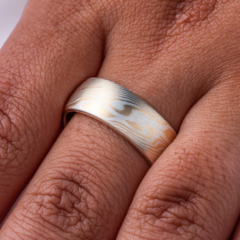 smooth surface domed wedding band, wide. smooth surface, layers of yellow gold and sterling silver twisting and running on a diagonal pattern around the ring