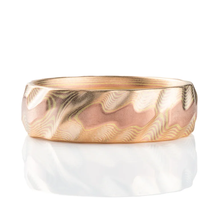 Gold mokume gane ring carved to look like three dimensional small waves rippling on the surface of the ocean. Made in a subtle metal combination with low contrasting red and green gold. Green gold is a pale yellow color.