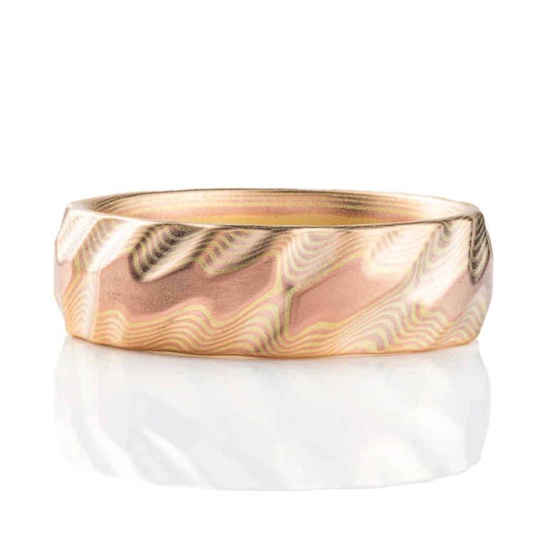 Gold mokume gane ring carved to look like three dimensional small waves rippling on the surface of the ocean. Made in a subtle metal combination with low contrasting red and green gold. Green gold is a pale yellow color.