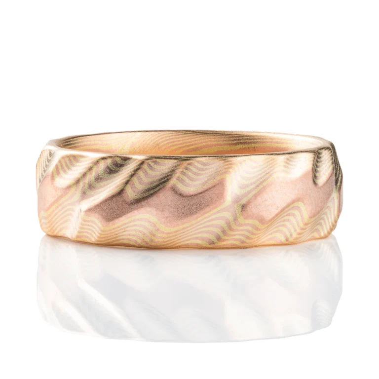 Gold mokume gane ring carved to look like three dimensional small waves rippling on the surface of the ocean. Made in a subtle metal combination with low contrasting red and green gold. Green gold is a pale yellow color.