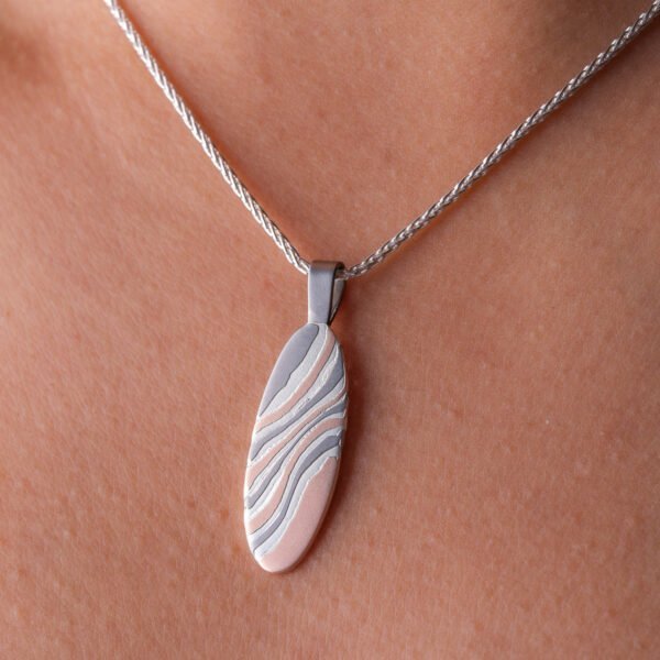 This simple and beautiful mokume gane pendant is made with 14kt red gold, palladium and sterling silver, on a silver chain and with an etched finish.