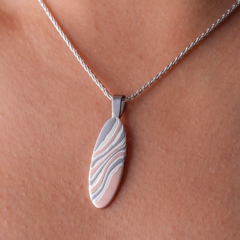 This simple and beautiful mokume gane pendant is made with 14kt red gold, palladium and sterling silver, on a silver chain and with an etched finish.