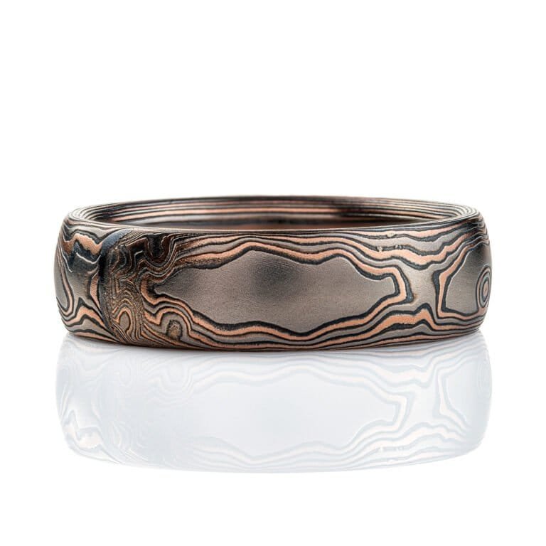 Domed mokume gane band, 6mm wide, made in a woodgrain style pattern, with layers of red gold, palladium and oxidized silver (black).