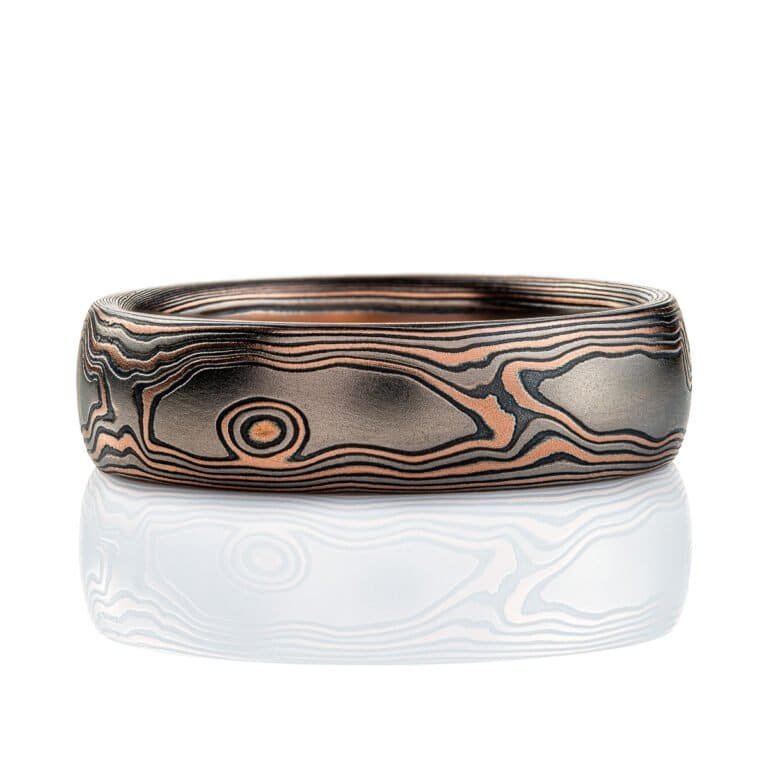 Domed mokume gane band, 6mm wide, made in a woodgrain style pattern, with layers of red gold, palladium and oxidized silver (black).