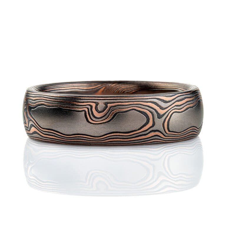 Domed mokume gane band, 6mm wide, made in a woodgrain style pattern, with layers of red gold, palladium and oxidized silver (black).