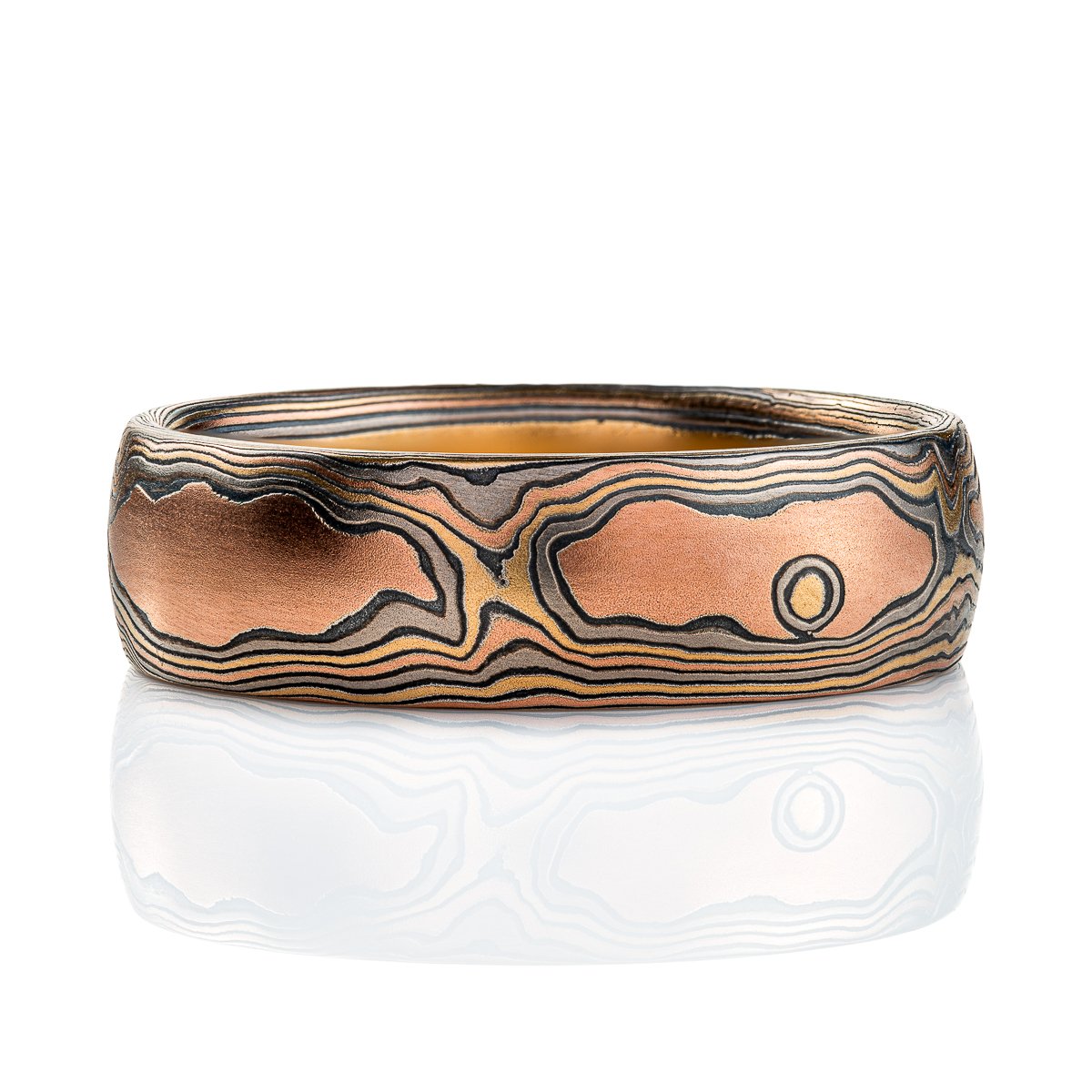 Wide men's style mokume gane band with a domed profile, made in a woodgrain style pattern to resemble wood, with layers of red gold and yellow gold alternating with oxidized silver (black).