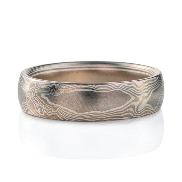 Silvery mokume gane ring made with layers of lighter and darker gray metals, pattern made to look like wood grain.