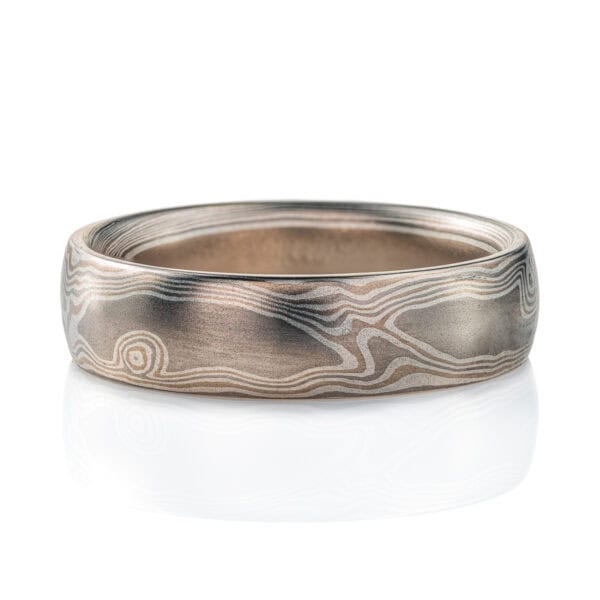 Silvery mokume gane ring made with layers of lighter and darker gray metals, pattern made to look like wood grain.