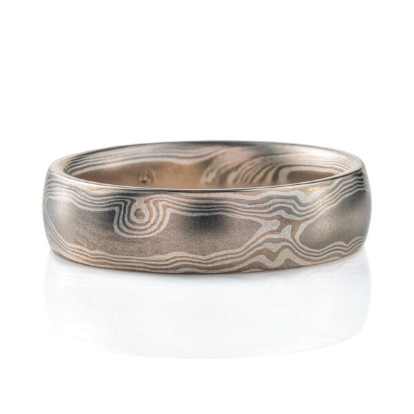 Silvery mokume gane ring made with layers of lighter and darker gray metals, pattern made to look like wood grain.