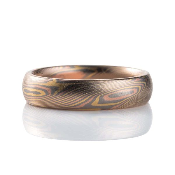 Slim mokume gane patterned ring with angled ellipse shapes running around the band, made with red gold, yellow gold and palladium, domed profile, smooth finish.