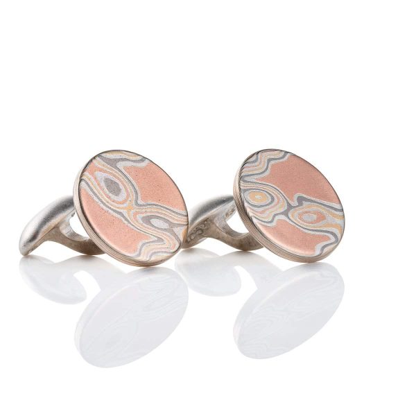 Pair of mokume gane patterned cufflinks, small and circular in shape, patterned to resemble wood grain.