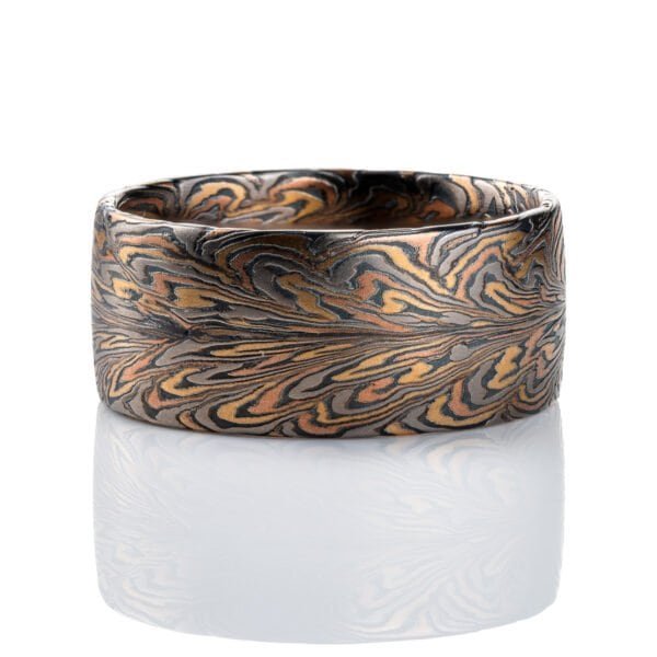 Wide mens ring mokume gane patterned to resemble the fibers of a feather, made with red and yellow gold, palladium, and oxidized silver (black) in thin layers.