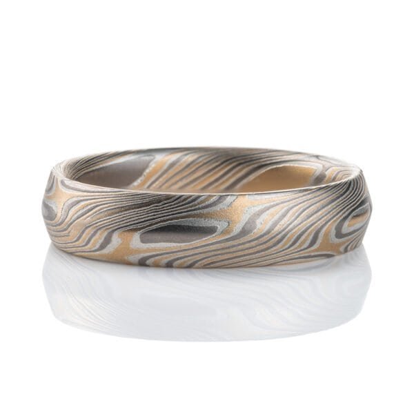 Mokume gane ring with beveled profile, patterned in long swooping lines and starburst like arcs. Made with yellow gold, silver and palladium.