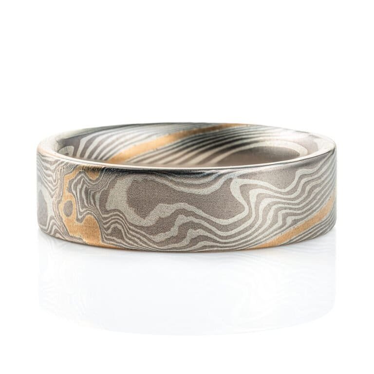 Flat profile ring made in mokume gane twist pattern, with layers of light and dark gray metals, and one layer of yellow gold.