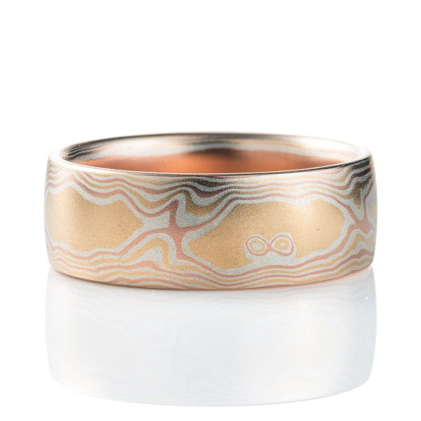 Warm toned mokume gane ring patterned to look like woodgrain. Made with layers of red gold, yellow gold and silver, with a smooth finish.