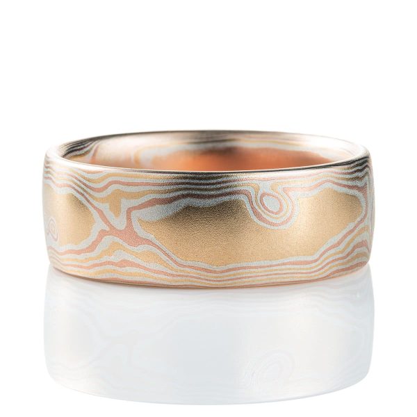 Warm toned mokume gane ring patterned to look like woodgrain. Made with layers of red gold, yellow gold and silver, with a smooth finish.