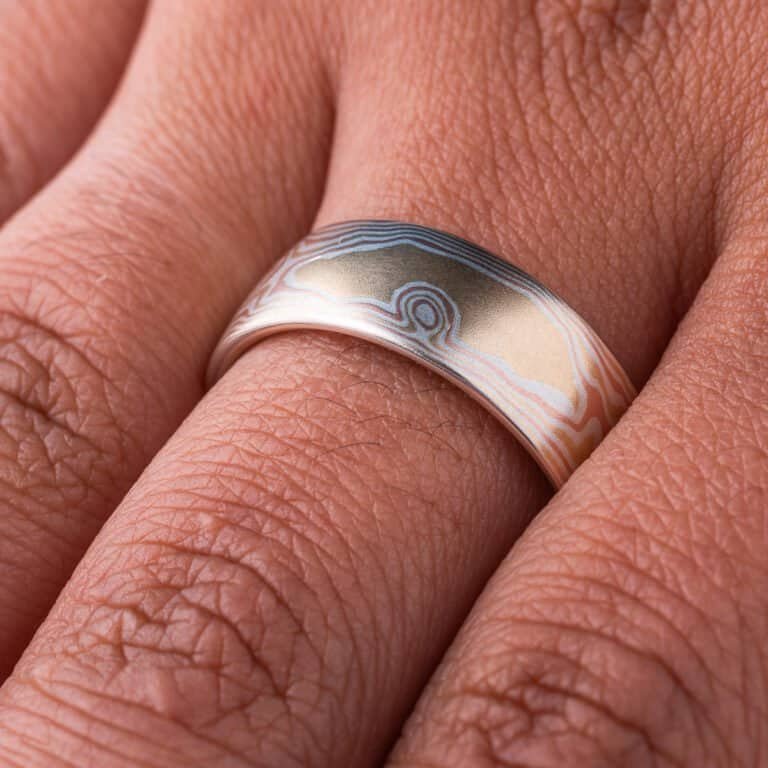 Warm toned mokume gane ring patterned to look like woodgrain. Made with layers of red gold, yellow gold and silver, with a smooth finish.