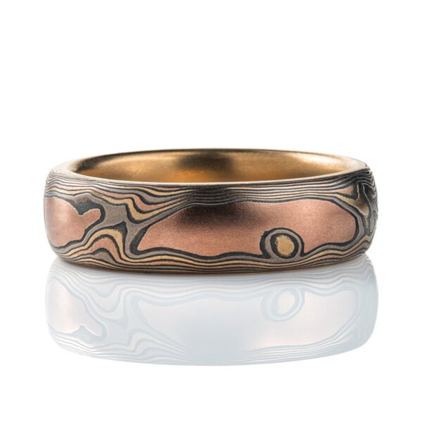 Mokume gane woodgrain patterned ring made with layers of red gold, yellow gold, palladium and oxidized silver (black), the ring is lined with a solid layer of yellow gold.