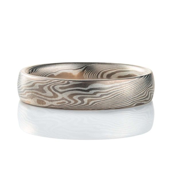 Domed, narrower mokume gane patterned ring, made in a light gray and dark gray metal, with pattern twisting and swirling around the band in a diagonal direction.
