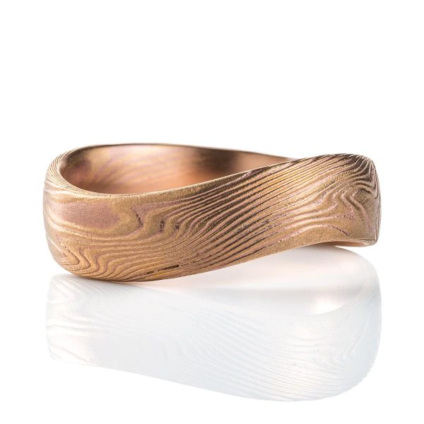 Mokume gane patterned ring with an undulating shape, made with red and yellow gold.