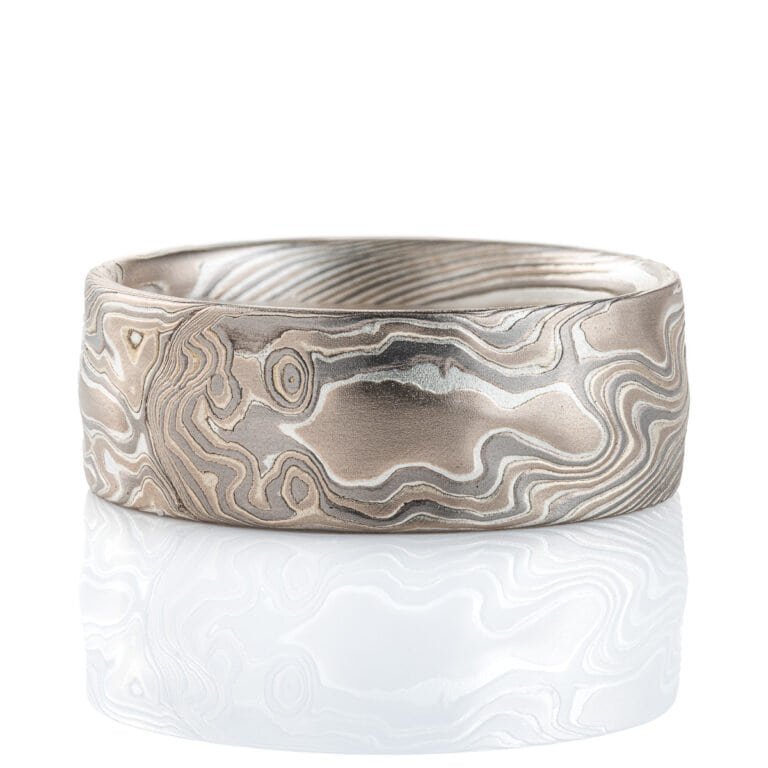 Wide men's mokume gane ring, etched for texture, and carved on the surface to add subtle ripples and waves. Made with palladium, silver and white gold.