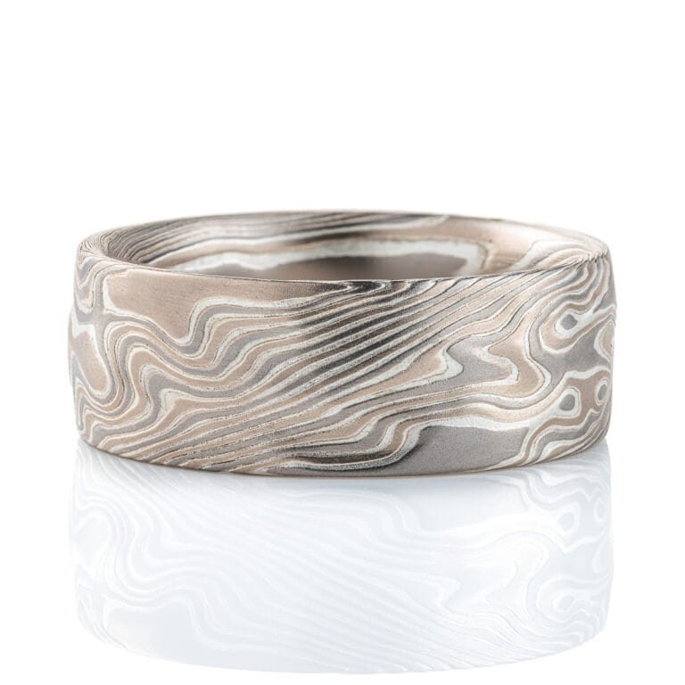 Wide men's mokume gane ring, etched for texture, and carved on the surface to add subtle ripples and waves. Made with palladium, silver and white gold.