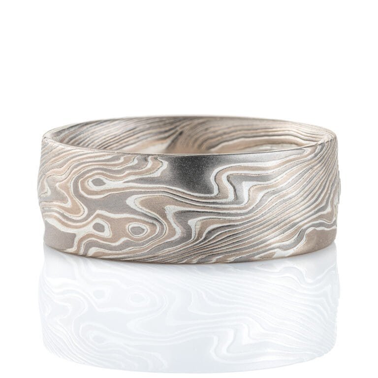 Wide men's mokume gane ring, etched for texture, and carved on the surface to add subtle ripples and waves. Made with palladium, silver and white gold.