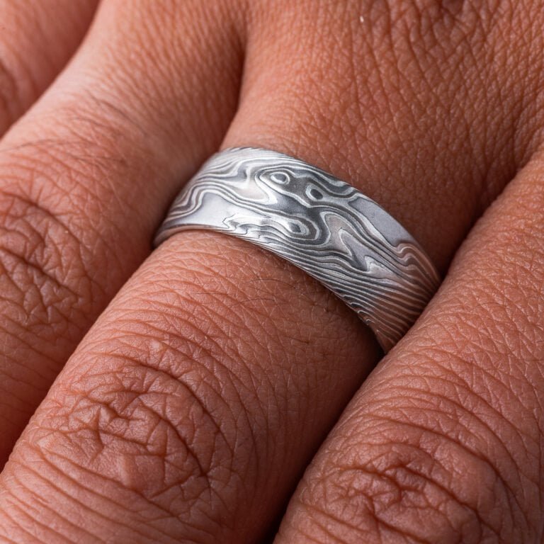 Wide men's mokume gane ring, etched for texture, and carved on the surface to add subtle ripples and waves. Made with palladium, silver and white gold.
