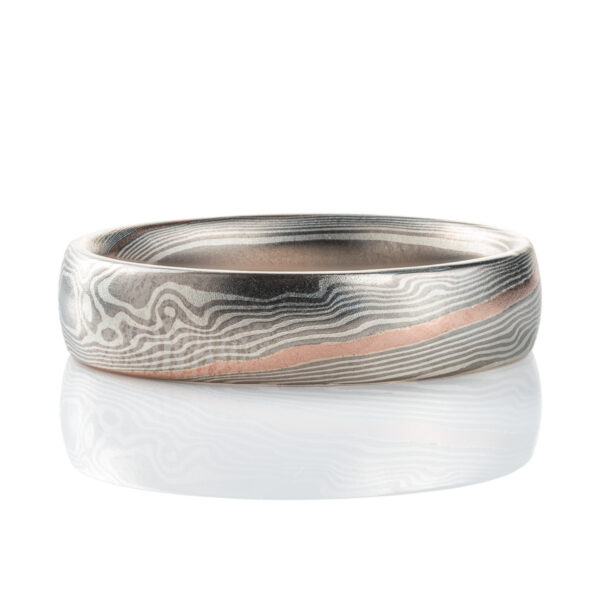 Smooth, domed, slender band patterned in mokume gane twist style, most of the ring is made in silver and palladium, with one stripe of red gold.