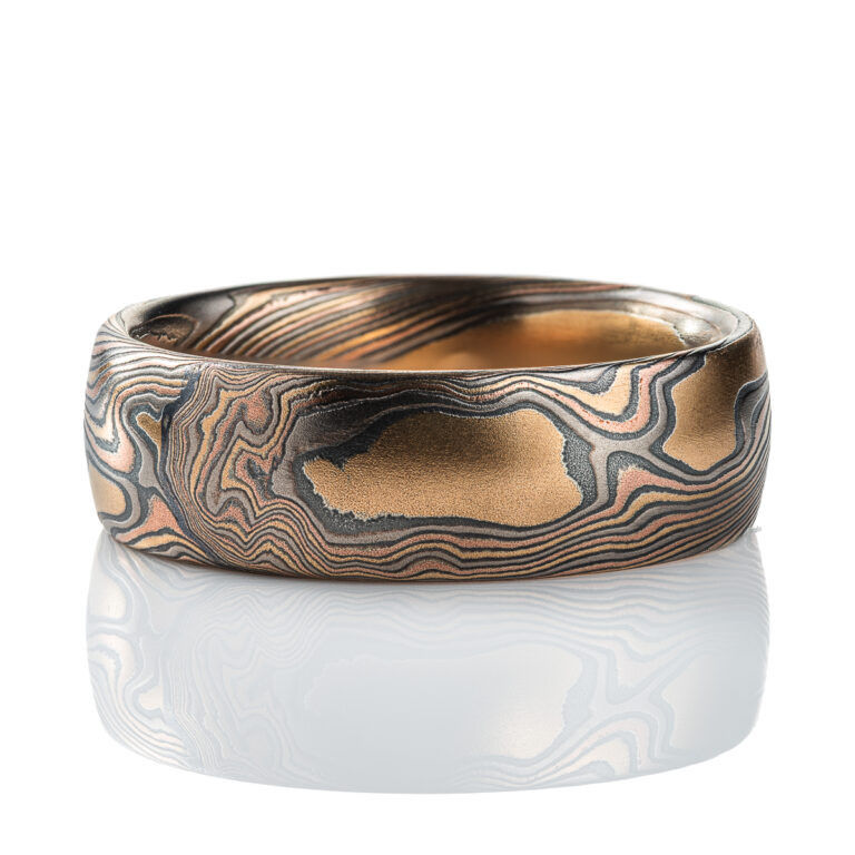 Mens mokume gane band made in twist pattern, with layers of red gold, yellow gold, palladium, and oxidized silver (black). .