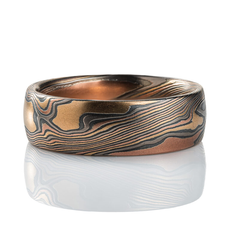 Mens mokume gane band made in twist pattern, with layers of red gold, yellow gold, palladium, and oxidized silver (black).