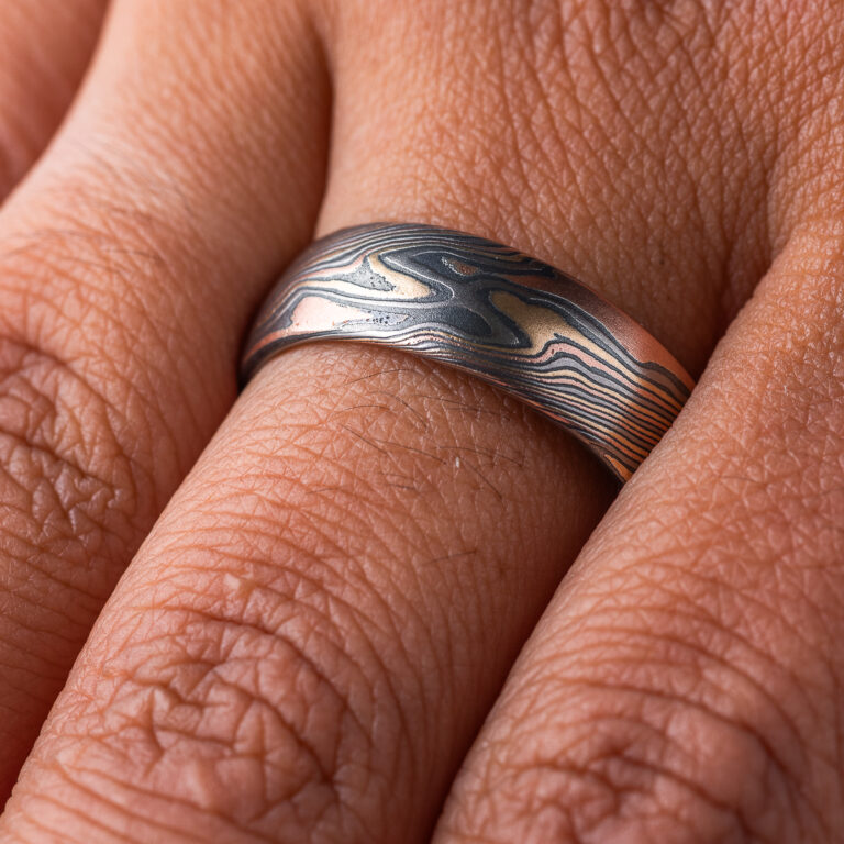 Mens mokume gane band made in twist pattern, with layers of red gold, yellow gold, palladium, and oxidized silver (black). .