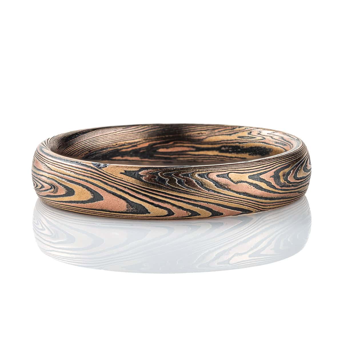 Intricately patterned mokume gane band with a twisting linear pattern, made with red and yellow gold and oxidized silver.