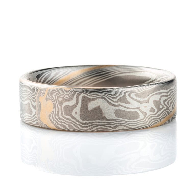 Wide flat profile mokume gane ring, patterned in twisting style, made with layers of palladium and silver for an overall gray palette, with one stripe of yellow gold.