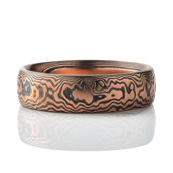 Red gold and oxidized silver mokume gane band, intricately patterned to resemble woodgrain or bark, with a domed profile.