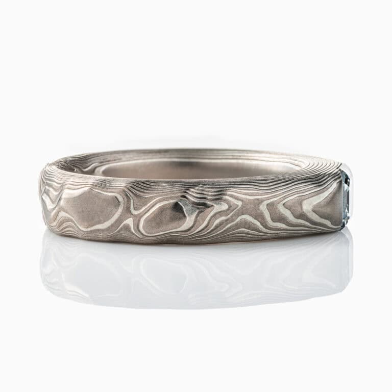 Textured mokume gane patterned ring, with three dimensional carving made to resemble rock. The ring is slightly thicker towards the top, to hold an asscher cut diamond that has been set flush into the ring.