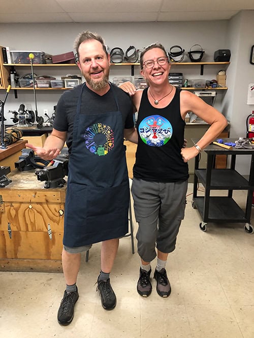 Man and woman standing side by side in a metalsmithing work shop. People in picture are Arn Krebs and Anne Wolf