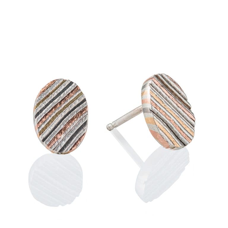 Mokume gane circular earrings patterned in a linear style, made with layers of red gold, yellow gold, palladium and silver.