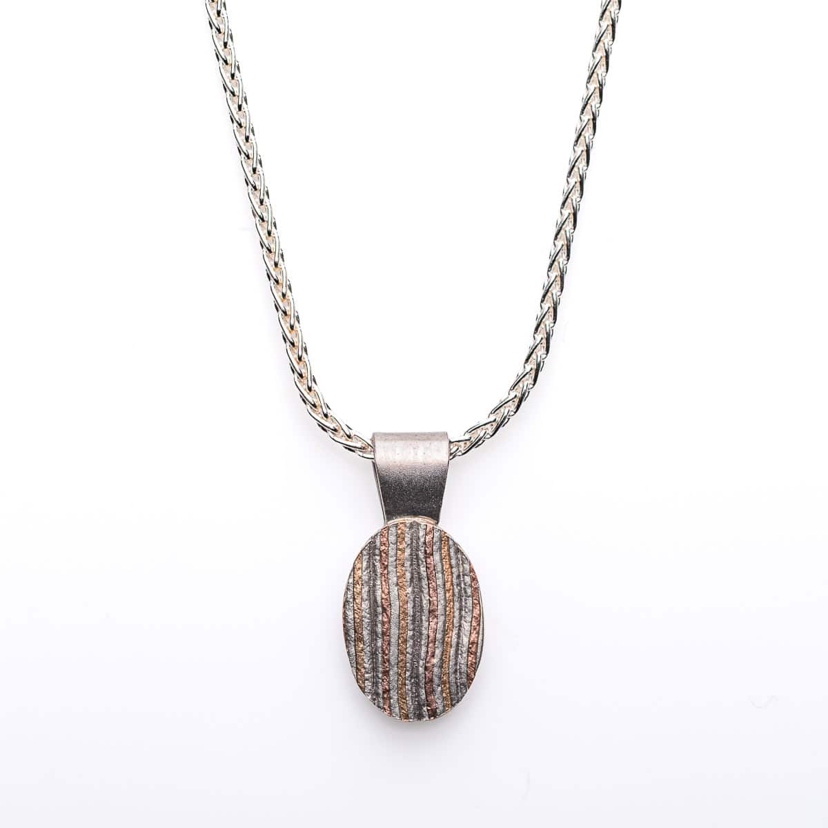 Small oval shaped mokume gane patterned pendant. Hanging on a silver chain.
