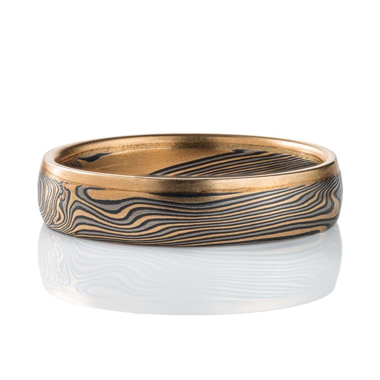 Mokume gane twisted band, with one solid strip of yellow gold running around one edge. The rest of the ring is made of layers of yellow gold, palladium and silver.