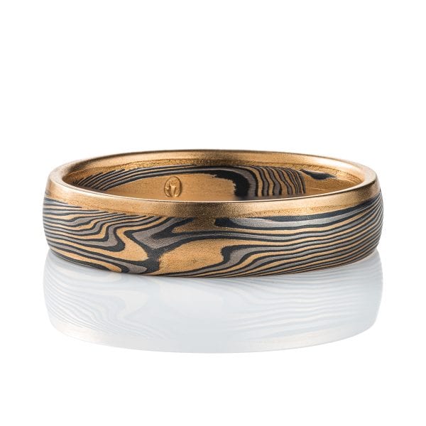 Mokume gane twisted band, with one solid strip of yellow gold running around one edge. The rest of the ring is made of layers of yellow gold, palladium and silver.