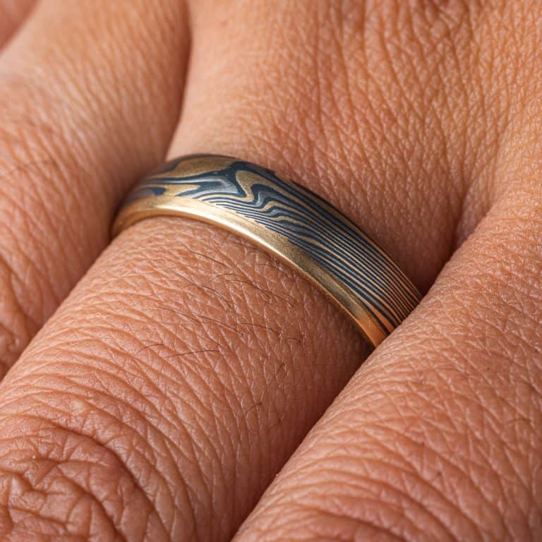 Mokume gane twisted band, with one solid strip of yellow gold running around one edge. The rest of the ring is made of layers of yellow gold, palladium and silver. .