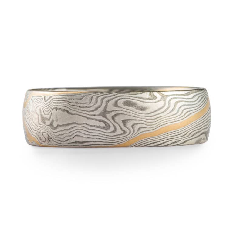 Mokume gane ring made in twist pattern, made of shibuichi and silver, with a single stripe of yellow gold.