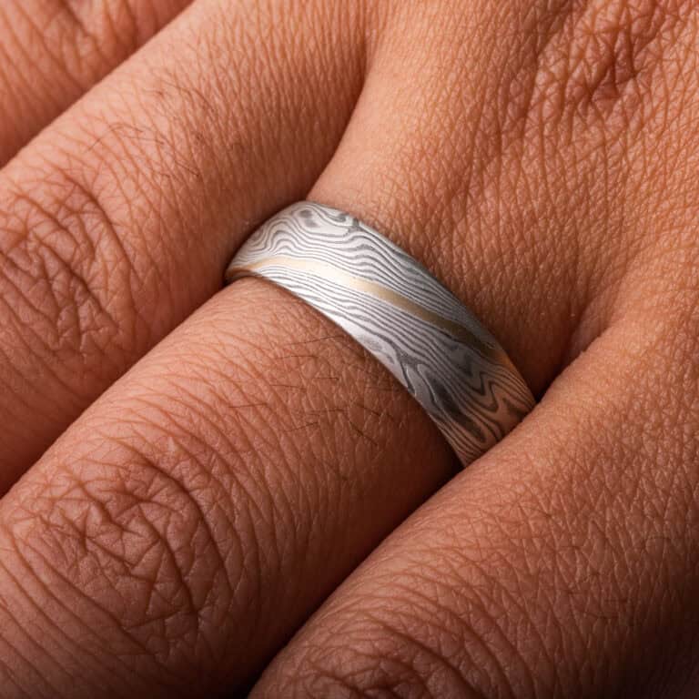 Mokume gane ring made in twist pattern, made of shibuichi and silver, with a single stripe of yellow gold.