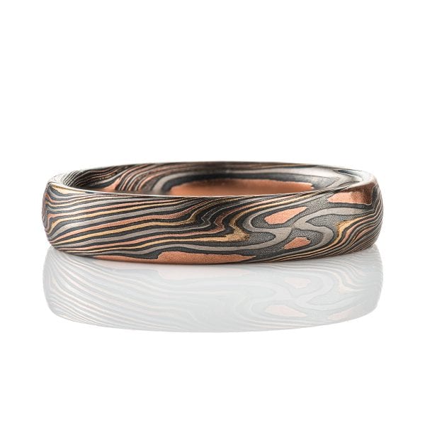 Mokume gane patterned band, made to look like woodgrain, made of layers of red gold, yellow gold, palladium, and oxidized silver.