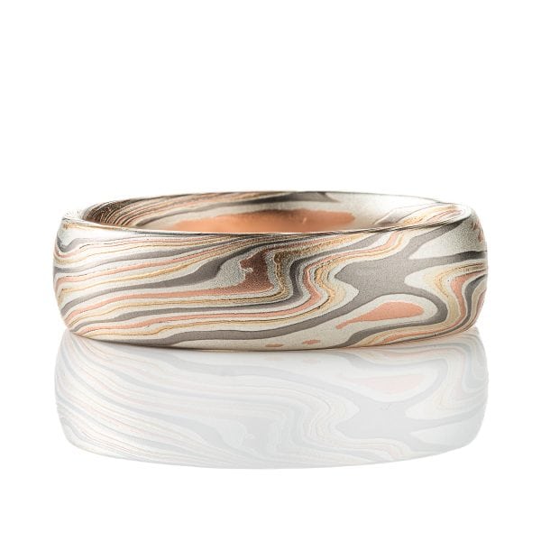 Mokume gane patterned band, twisting and organic flowing pattern, made of layers of red gold, yellow gold, palladium, and etched silver. The etching adds a subtle texture.